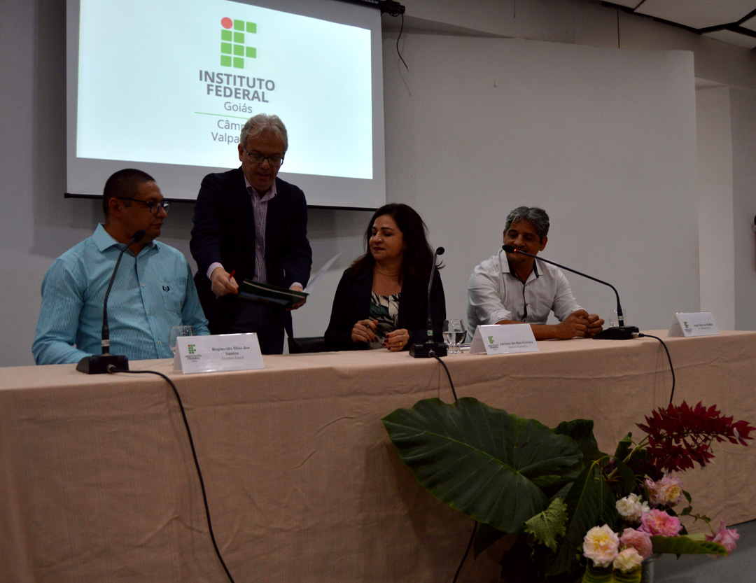 Momento da assinatura do termo de posse. Na mesa, da esquerda para a direita: Reginaldo, Adriana e João